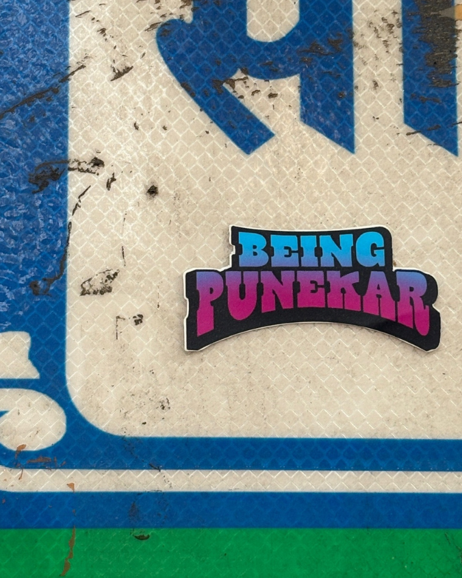 Colorful 'Being Punekar' sticker on a textured surface with blue and green elements.