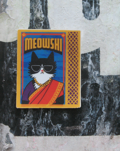 Sticker of a cat in a sari with 'MEOWSHI' text on a textured background